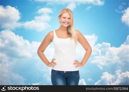 people, holidays, style and body type concept - smiling young woman in blank white shirt and jeans over blue sky and clouds background