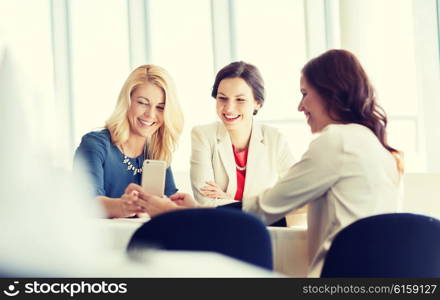 people, holidays, technology and lifestyle concept - happy women with smartphone at restaurant