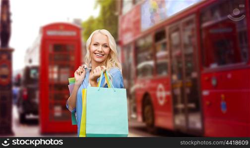 people, holidays, tourism, travel and sale concept - young happy woman with shopping bags over london city street background