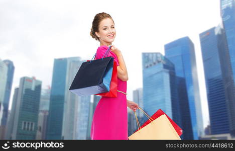 people, holidays, tourism, travel and sale concept - young happy woman with shopping bags over singapore city skyscrapers background