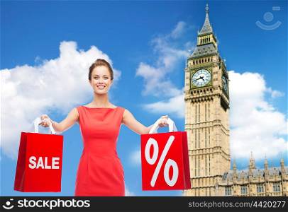 people, holidays, tourism, travel and sale concept - young happy woman with shopping bags with percent sign over big ben clock tower background