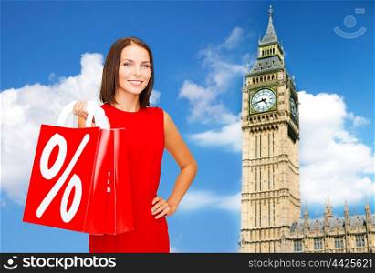 people, holidays, tourism, travel and sale concept - young happy woman with shopping bags with percent sign over big ben clock tower background