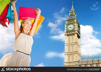 people, holidays, tourism, travel and sale concept - young happy woman with shopping bags over big ben clock tower background