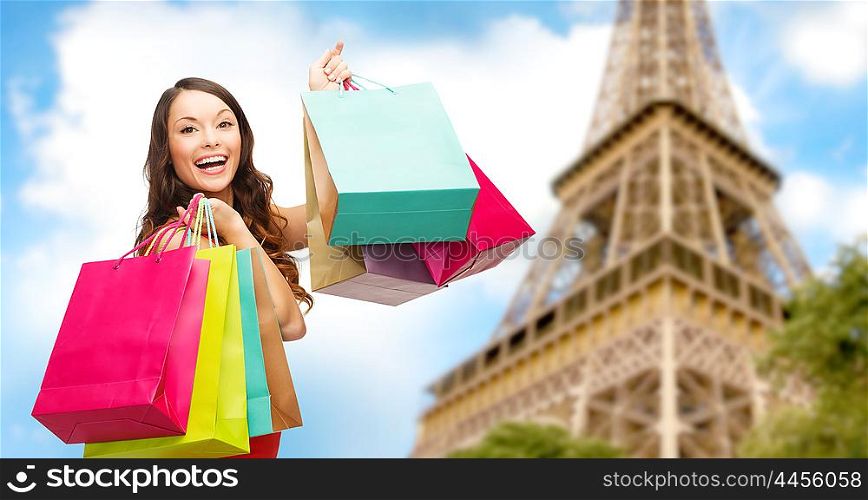 people, holidays, tourism, travel and sale concept - young happy woman with shopping bags over over paris eiffel tower background