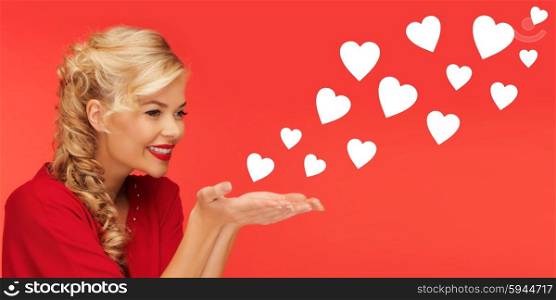 people, holidays, valentines day and love concept - lovely woman in red clothes sending heart shapes from on palms of her hands over red background