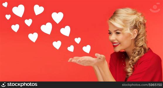 people, holidays, valentines day and love concept - lovely woman in red clothes sending heart shapes from on palms of her hands over red background