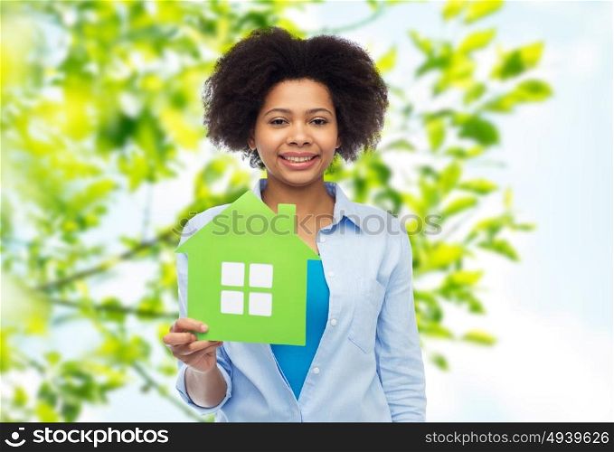 people, home and real estate concept - happy african american young woman with green house icon over green natural background. happy african american woman with green house icon