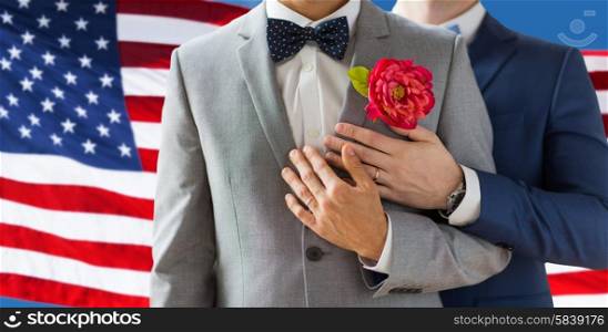 people, homosexuality, same-sex marriage and love concept - close up of happy married male gay couple in suits with buttonholes and bow-ties on wedding over american flag background