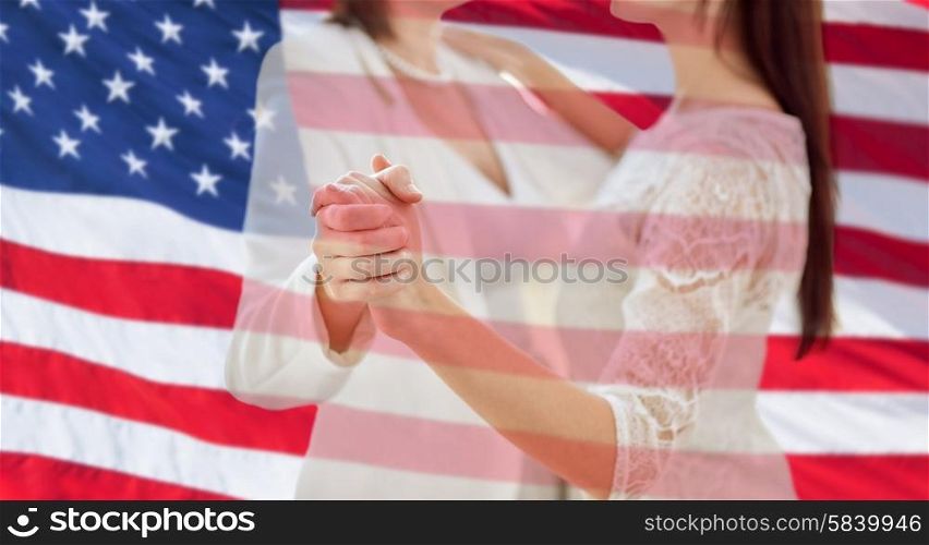 people, homosexuality, same-sex marriage and love concept - close up of happy married lesbian couple dancing over american flag background