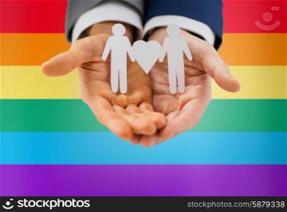 people, homosexuality, same-sex marriage and love concept - close up of happy male gay couple holding paper cutout love symbol over rainbow flag background