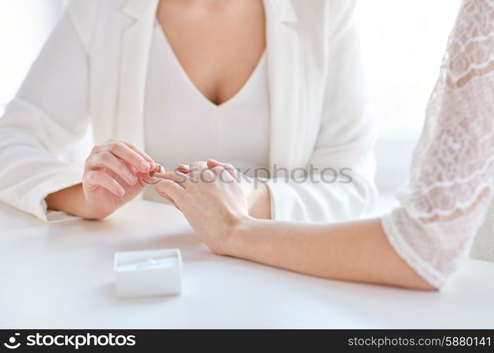 people, homosexuality, same-sex marriage and love concept - close up of happy lesbian couple hands putting on wedding ring