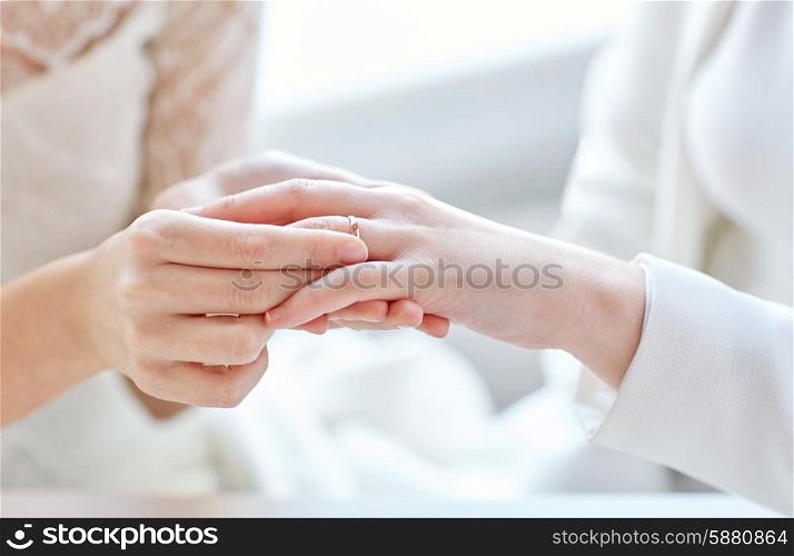 people, homosexuality, same-sex marriage and love concept - close up of happy lesbian couple hands putting on wedding ring