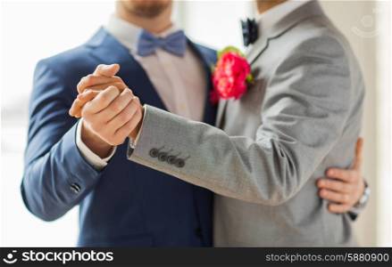 people, homosexuality, same-sex marriage and love concept - close up of happy male gay couple holding hands and dancing on wedding