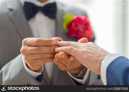 people, homosexuality, same-sex marriage and love concept - close up of happy male gay couple hands putting wedding ring on