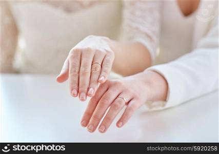 people, homosexuality, same-sex marriage and love concept - close up of happy lesbian couple hands showing wedding rings on