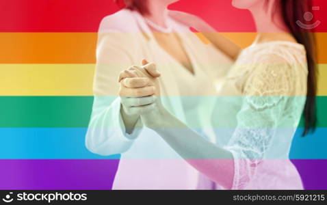 people, homosexuality, same-sex marriage and love concept - close up of happy married lesbian couple dancing over rainbow flag stripes background