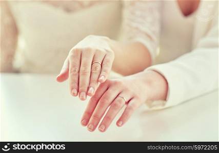 people, homosexuality, same-sex marriage and love concept - close up of happy lesbian couple hands showing wedding rings on