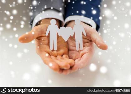 people, homosexuality, same-sex marriage and love concept - close up of happy male gay couple holding paper cutout love symbol over snow effect