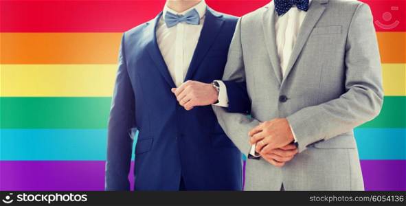 people, homosexuality, same-sex marriage and love concept - close up of happy male gay couple holding hands on wedding over rainbow flag background