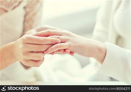 people, homosexuality, same-sex marriage and love concept - close up of happy lesbian couple hands putting on wedding ring