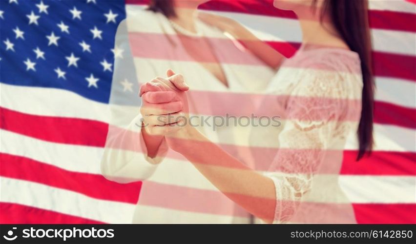 people, homosexuality, same-sex marriage and love concept - close up of happy married lesbian couple dancing over american flag background