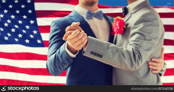 people, homosexuality, same-sex marriage and love concept - close up of happy male gay couple holding hands and dancing on wedding over american flag background