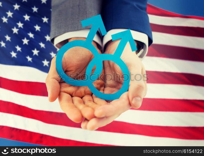 people, homosexuality, same-sex marriage and love concept - close up of happy male gay couple holding paper cutout love symbol over american flag background