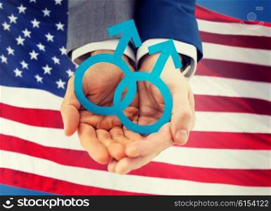 people, homosexuality, same-sex marriage and love concept - close up of happy male gay couple holding paper cutout love symbol over american flag background