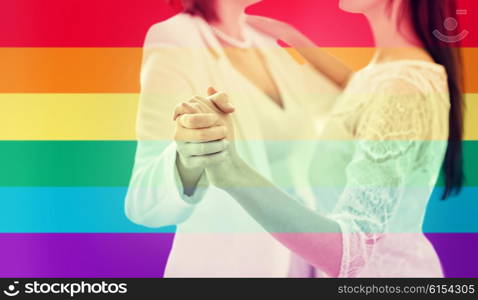 people, homosexuality, same-sex marriage and love concept - close up of happy married lesbian couple dancing over rainbow flag stripes background