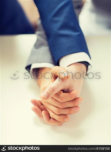 people, homosexuality, same-sex marriage and love concept - close up of happy male gay couple holding hands on wedding