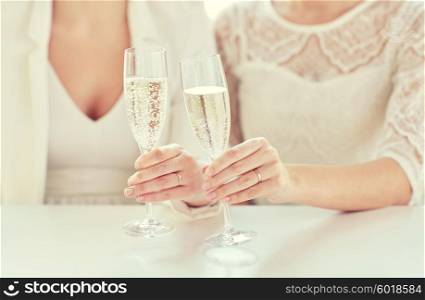 people, homosexuality, same-sex marriage, celebration and love concept - close up of happy married lesbian couple hands holding champagne glasses