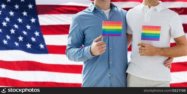 people, homosexuality, same-sex marriage, gay and love concept - close up of happy male gay couple hugging and holding rainbow flags over american flag background