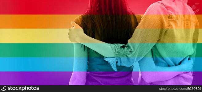 people, homosexuality, same-sex marriage, gay and love concept - close up of happy lesbian couple hugging over rainbow flag stripes background