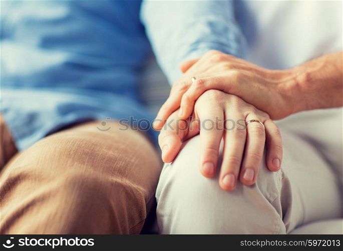 people, homosexuality, same-sex marriage, gay and love concept - close up of happy male gay couple holding hands with wedding rings on