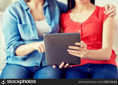 people, homosexuality, same-sex marriage, gay and love concept - close up of happy lesbian couple with tablet pc computer sitting on sofa at home