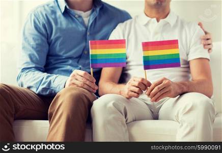 people, homosexuality, same-sex marriage, gay and love concept - close up of happy male gay couple hugging and holding rainbow flags at home