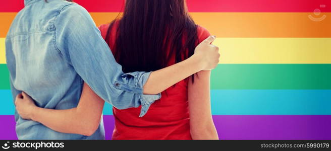 people, homosexuality, same-sex marriage, gay and love concept - close up of happy lesbian couple hugging over rainbow flag background