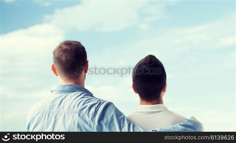 people, homosexuality, same-sex marriage, gay and love concept - close up of happy male gay couple or friends hugging from back over blue sky background