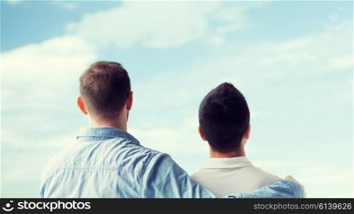 people, homosexuality, same-sex marriage, gay and love concept - close up of happy male gay couple or friends hugging from back over blue sky background