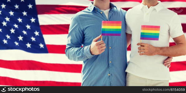 people, homosexuality, same-sex marriage, gay and love concept - close up of happy male gay couple hugging and holding rainbow flags over american flag background