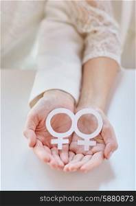people, homosexuality, same-sex marriage, gay pride and love concept - close up of happy lesbian couple hands holding white paper venus symbol