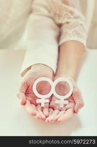 people, homosexuality, same-sex marriage, gay pride and love concept - close up of happy lesbian couple hands holding white paper venus symbol