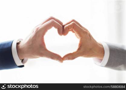 people, homosexuality, same-sex marriage, gesture and love concept - close up of happy male gay couple hands showing heart hand sign