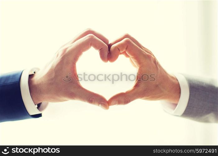 people, homosexuality, same-sex marriage, gesture and love concept - close up of happy male gay couple hands showing heart hand sign