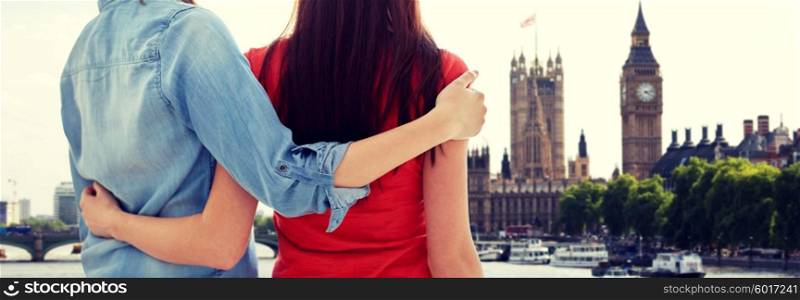 people, homosexuality, same-sex marriage, travel and gay love concept - close up of happy lesbian couple hugging over big ben and houses of parliament in london background