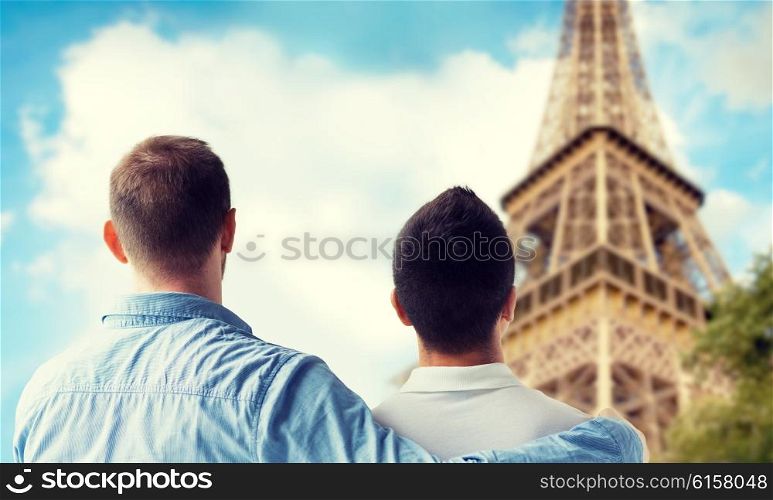 people, homosexuality, same-sex marriage, travel and love concept - close up of happy male gay couple hugging from back over paris eiffel tower background
