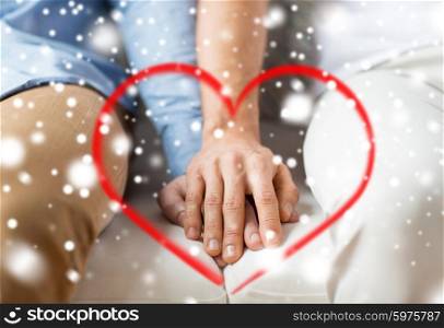 people, homosexuality, same-sex marriage, valentines day and love concept - close up of happy male gay couple holding hands with red heart shape and snow effect