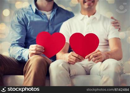 people, homosexuality, same-sex marriage, valentines day and love concept - close up of happy gay male couple with red hearts over holidays lights background
