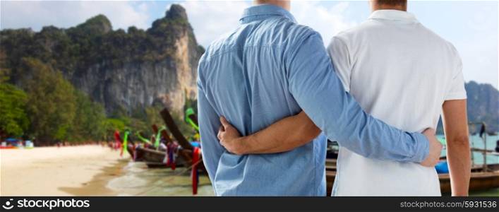 people, homosexuality, travel and love concept - close up of happy male gay couple hugging from back over thailand beach background
