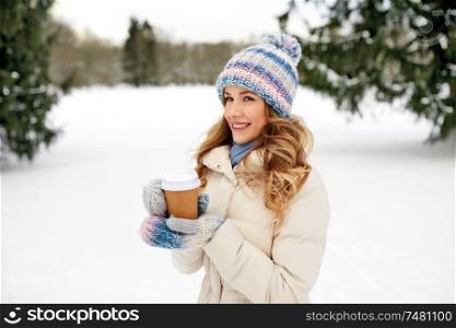 people, hot drinks and leisure concept - happy woman drinking takeaway coffee outdoors in winter. happy woman drinking coffee outdoors in winter